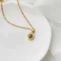 Dettaglio di una collana dorata con ciondolo in gemma nera su un vassoio bianco - Pietra Preziosa Nera