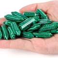 Polished malachite double-pointed hexagonal crystal pendants held in hand for scale - Malachite