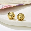 Macro shot of two vintage golden hollow round beads with detailed floral engravings for DIY jewelry - Style 4