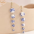 Macro shot of blue and white porcelain beads with golden tassels and rhinestone details - Long Style