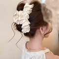 Détail d'une pince à cheveux à volants crème portée élégamment dans un chignon - Grande Pince à Cheveux Plissée en Tissu / Blanc