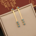 Orecchini a catena dorata con ciondoli occhio greco blu su una scatola portagioie - Orecchini