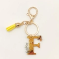 Detail view of letter F keychain with honeycomb pattern, yellow tassel and golden clasp - Letter F
