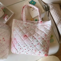 Gros plan d'un sac cabas matelassé à fleurs avec motifs cœurs et étiquette - Rose Cerise Nœud Floral