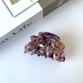 Pince à cheveux fleur violette en acétate avec perles dorées posée sur un magazine - Café Floral