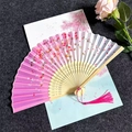 Close-up of pink cherry blossom folding fan with silk fabric and decorative tassel - Cherry Blossom Rain - Gradient Pink
