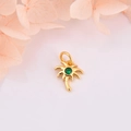 Détail macro d'un pendentif palmier doré avec zircon vert sur un fond floral doux - Pierre précieuse verte