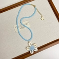 Detail of blue beaded necklace featuring a shell flower pendant and starfish charm - Style H Blue Shell Flower