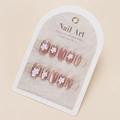 Close-up of pink press-on nails with white floral patterns on a beige display card - By1581 / Phototherapy Glue Style