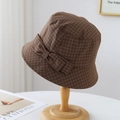 Detailed view of a brown plaid bucket hat with a bow on a wooden stand - Coffee Plaid