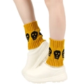 Yellow knitted leg warmers with black skull patterns shown on a model's legs - One Size / Ginger Yellow