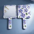 Handheld floral mirror with 3D embossed blue-purple flowers and matte white finish - 16 Splendid Years