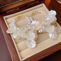 Detail van elegante gouden oorringen met witte parels en bloembladhangers in een doosje - Wit (Zilveren oorbelpost)