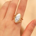 Primer plano de anillo vintage dorado con turquesa blanca ovalada y banda con textura trenzada - Estilo Resina Blanca / Oro KC