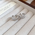 Primer plano de ear cuffs de plata pulida en un joyero de terciopelo beige de tacto suave - Plateado