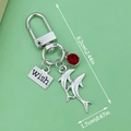 Blue resin dolphin keychain with silver wish tag and red gemstone charm detail - Dolphin