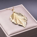 Macro shot of leaf pendant with detailed gold plating on a premium jewelry gift box - Pendant Necklace / Gold