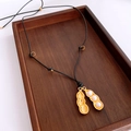 Makroaufnahme von goldenem Erdnuss-Anhänger mit Perlen auf einem Holztablett - Gold (Erdnussform)