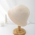 Detail of a beige knitted bucket hat with thick ribbed texture on a wooden stand - Adjustable / Beige