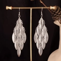 Detailed view of silver multi-layer leaf tassel earrings on a golden jewelry stand - Frosted Marquise / Silver