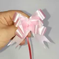 Pink pearlized gift bow with ribbon tail held by hand for festive box decoration - Solid Light Pink