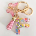 Detailed view of pink resin letter F keychain with sequins, butterfly and suede tassel - Letter F