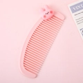 Cute pink plastic crescent comb for kids featuring a cartoon rabbit topper on a soft background - Rabbit