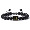 Vue détaillée du bracelet en pierre de lave avec perle carrée dorée et lettre H gravée - Lettre H(H)