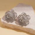 Macro shot of silver hollow-out rose earrings on textured stone base with metal finish - Silver (Silver Pin) / Silver