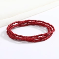 Detailed close-up of vibrant red multi-layer beaded waist chain on a white fabric background - Red