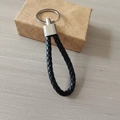 Detalle de un llavero de cuero trenzado negro con anillo de metal plateado - Negro