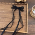 Dettaglio di un fiocco per capelli in pizzo nero con nastri su un vassoio di legno - Nero