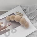 Close-up of beige faux fur plush hair claw clip on an open magazine background - Khaki