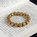 Detailed view of green sandalwood prayer beads with natural wood grain on a book - Green Sandalwood Classical Beads / 12mm*17 Beads / Yellow-Green
