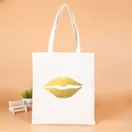 Close-up of white canvas tote bag featuring a gold foil lip print for bridal parties - Style E (Gold Lips)