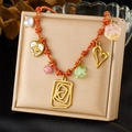 Bunte gewebte Halskette mit Goldherzen und Blumenperlen auf beiger Schmuckschatulle - Mehranhänger Bunter Seilstil (N3513)