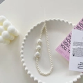 Detail of beaded phone strap with white pearls and iridescent heart charms on a plate - Pearl White Heart Bracelet