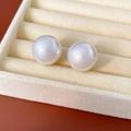 Primo piano di orecchini a perla bianca lucida su un espositore per gioielli in velluto - 1.7cm / Bianco