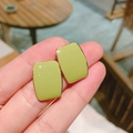 Pale green rectangular stud earrings with gold plating shown in a hand perspective - Green Rectangular Stud Earrings