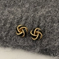 Detail of vintage gold and black enamel knot earrings on a grey felt background - Black Concentric Knot - Gold Plated
