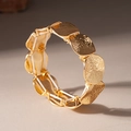 Detailed close-up of golden elastic bracelet with hammered texture geometric discs - Gold