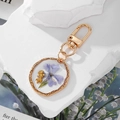 Golden keychain featuring a handmade purple dried flower and mini bear inside resin charm - Blue Flower
