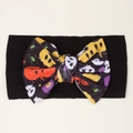 Macro detail of Halloween baby headband with pumpkin and ghost print bow on black fabric - Black