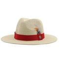 Detail of straw fedora hat featuring red grosgrain ribbon, feather, and vintage metal badge - Beige
