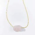 Detailed view of an irregular raw pink crystal stone pendant on a gold-tone chain necklace - Rose Quartz