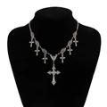Detalle de collar de cruz gótica plateada con cuentas de vidrio rojas en un soporte - Cruz de Flores de Plata
