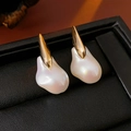 Detailed close-up of Baroque irregular pearl earrings with gold plating on black leather - Silver Needle Baroque Pearl Style / Real Gold Plated Gold