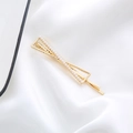 Detail shot of golden geometric hair clip with white faux pearls on white silk fabric - Bowtie Pearl