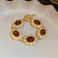 Detailansicht eines Goldarmbands mit Bernstein-Edelsteinen und Knebelverschluss in Schale - Armband-Gold-Rot