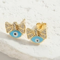 Macro-opname van gouden strik oorbellen met blauw boze oog op een stenen achtergrond - Strik Stijl / Blauwe Strik